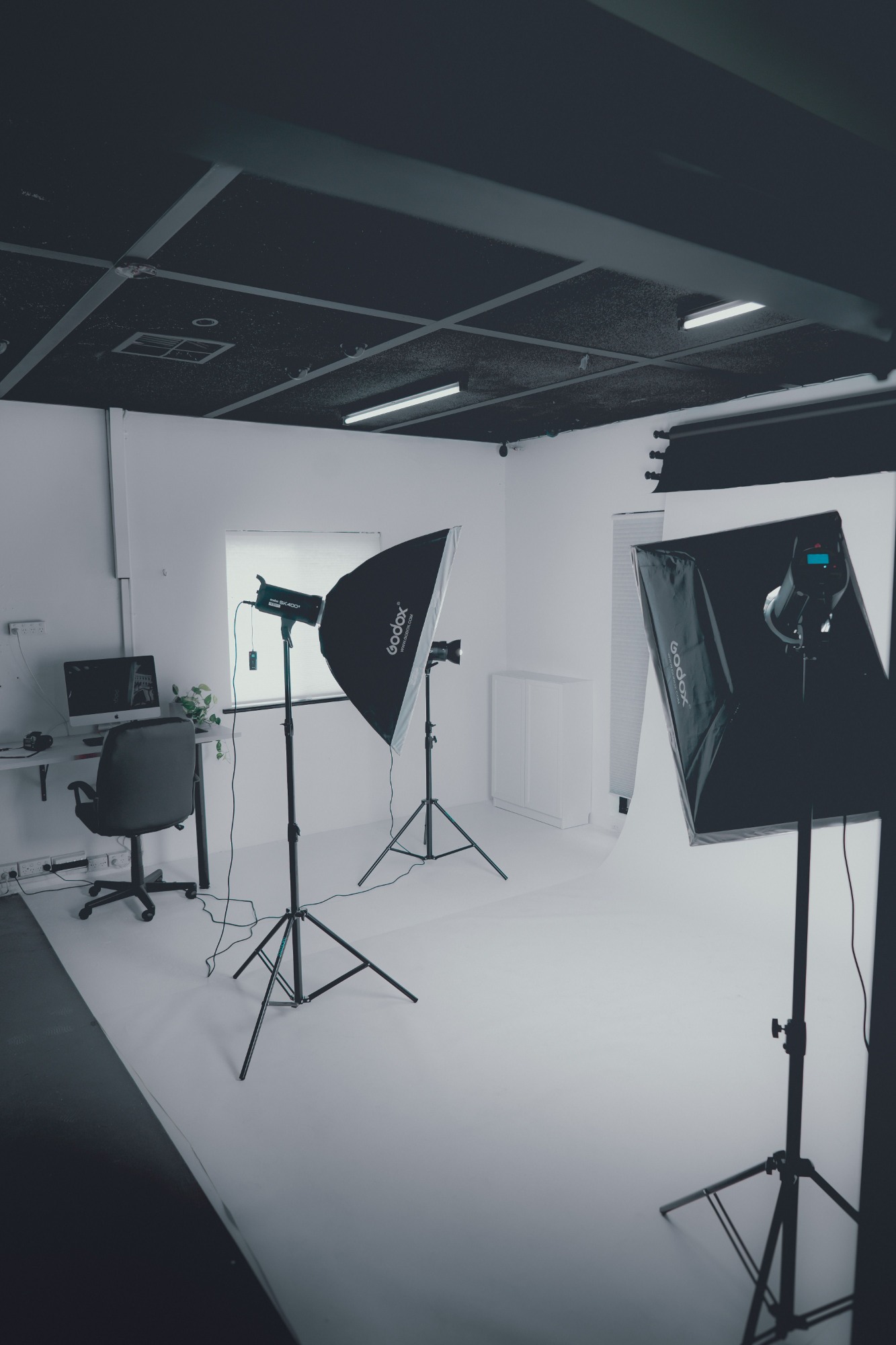 Fotostudio met verlichting en een werkplek in een lichte, minimalistische ruimte.